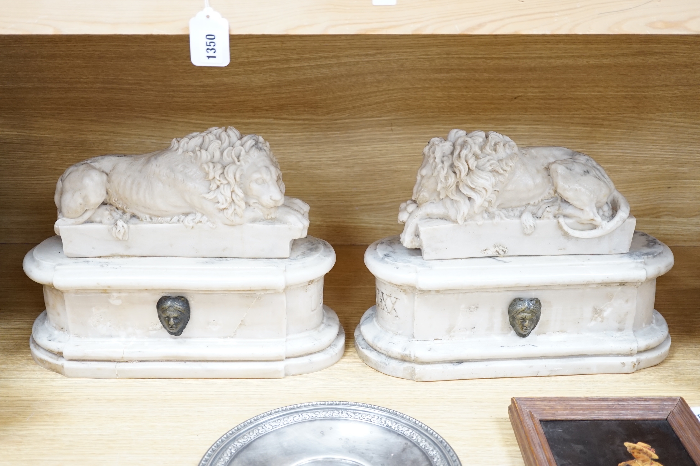 After the Antique. A pair of marble resin models of the Medici lions, each seated upon an oblong plinth, applied with bronze masks, inscribed LECXX, 41cm long, 15cm deep, 29cm high